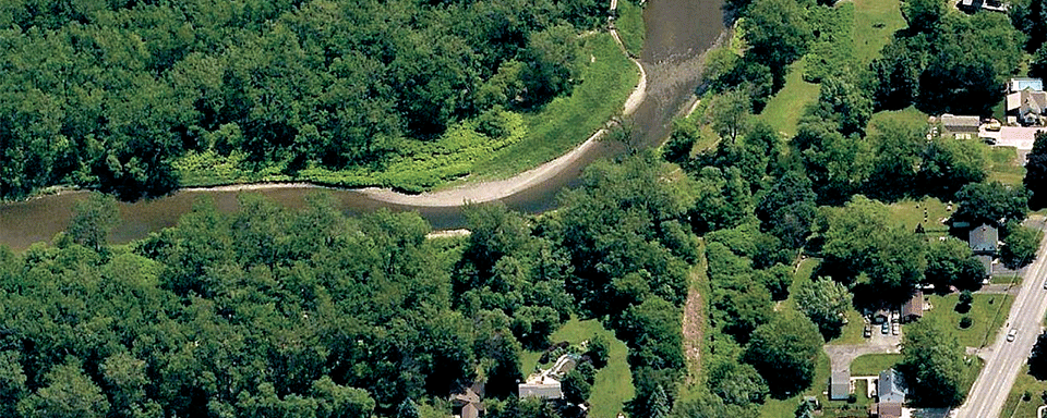 Overhead image of a river flowing next to houses.